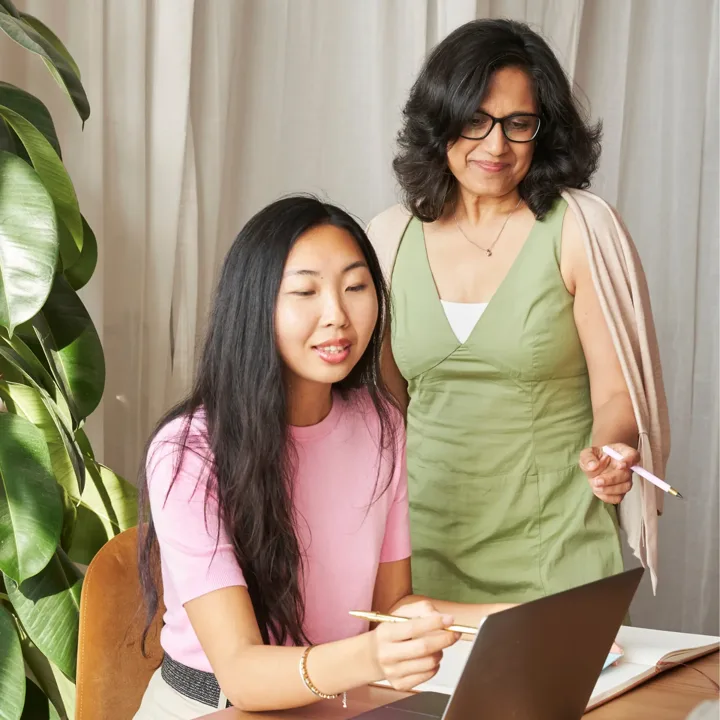 An advisor and a student reviewing coursework on a laptop